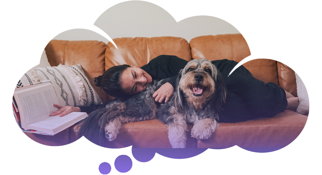 Woman laying on couch with fluffy happy dog